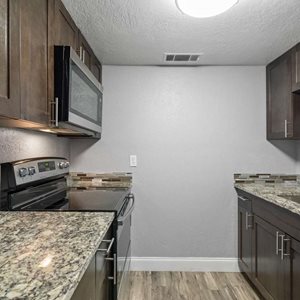 A kitchen with granite countertops and wooden cabinets.